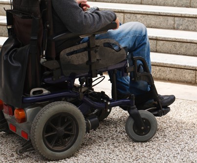 Personne en chaise roulante devant un escalier