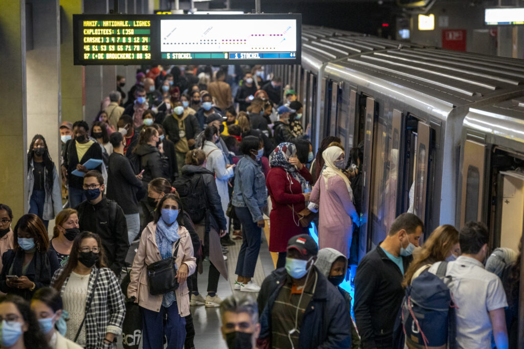 Station de métro avec une rame et de nombreux passagers en attente